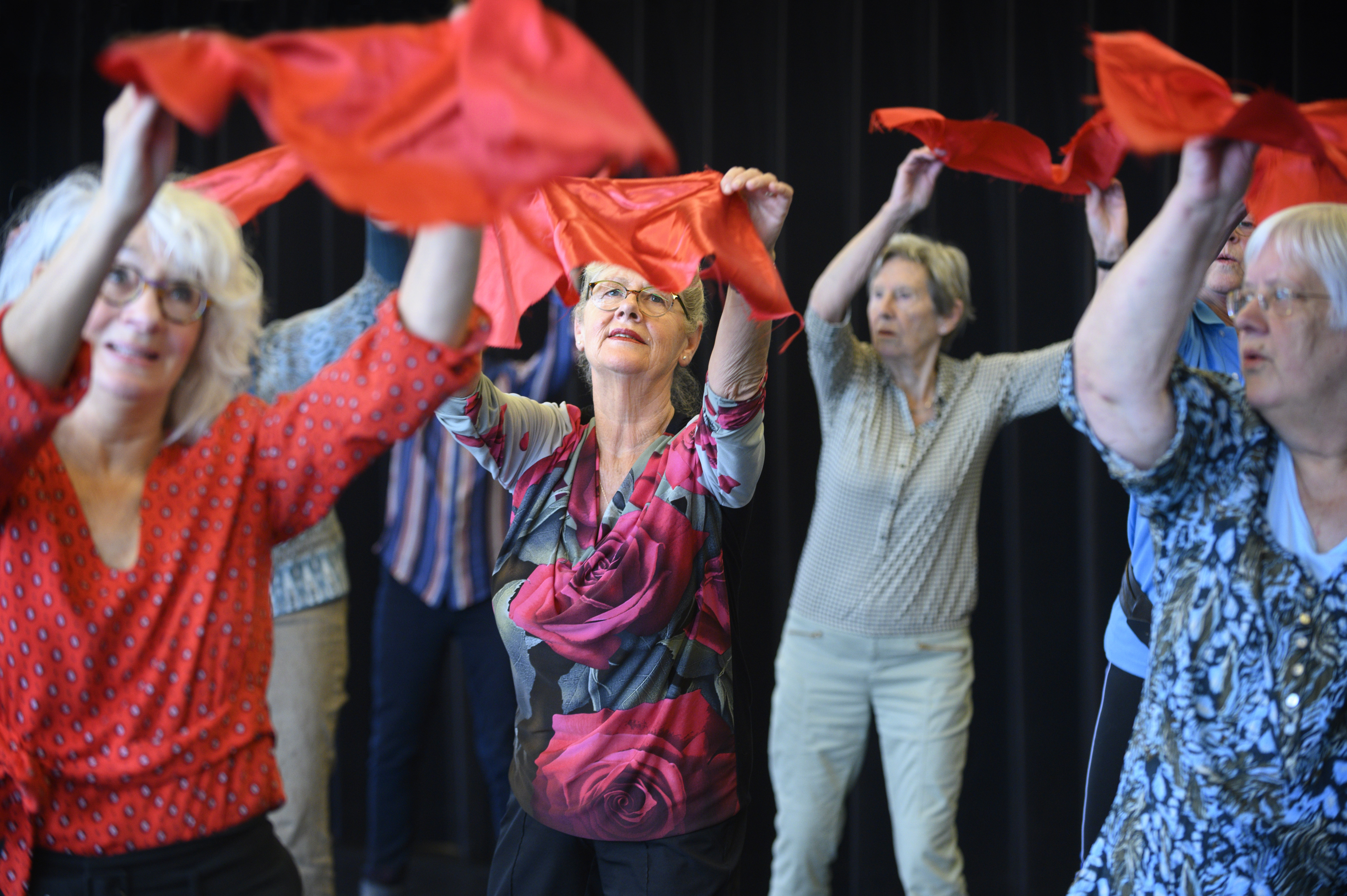 Senioren dansen met rode doeken boven het hoofd