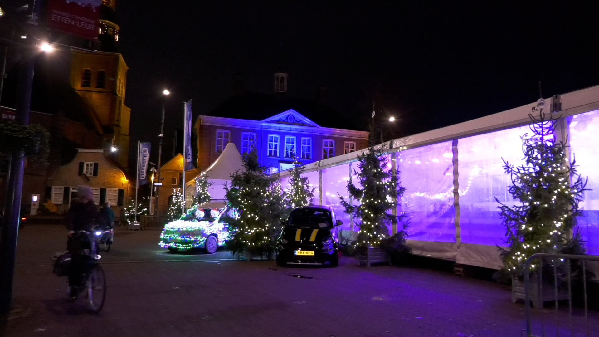 De schaatstent is omringd met bomen en lichtjes.