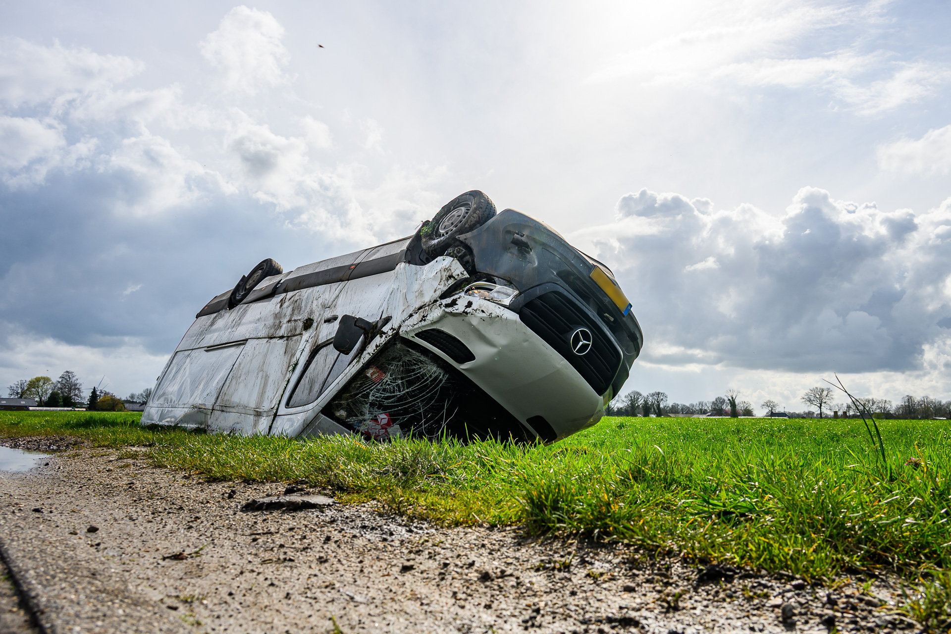 Pakketbezorger eindigt met bestelbus op zijn kop in sloot na aanrijding